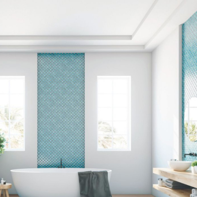 Bright and modern bathroom with a freestanding white bathtub, teal mosaic tile accent walls, light wood flooring, and natural light streaming through tall windows.